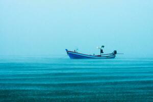 Fishing boat on the sea with raining in the sea. photo