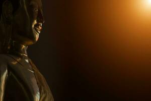 Portrait of a golden Buddha statue in the dark rooms with sunlight photo