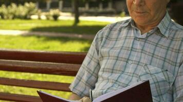 Senior homem escreve dentro dele caderno em a Banco video