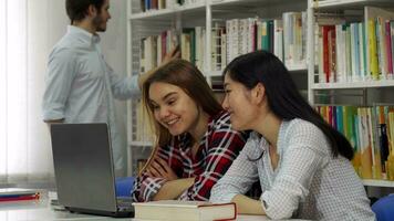 dois menina estude em computador portátil às a biblioteca video