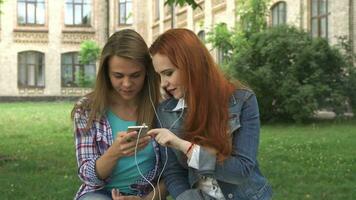 hembra estudiantes escucha a música en teléfono inteligente en instalaciones video