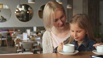 Little girl drinks tea at the cafe video