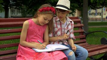 pequeno menina desenha em 1 página do caderno e dela amigo em outro video