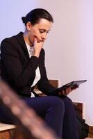 Stressed businesswoman under pressure to finish job deadline doing overtime at night. Serious entrepreneur working on job project sitting on staircase of business building at night hours for job. photo