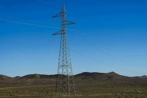 an electricity tower in the desert with a blue sky photo