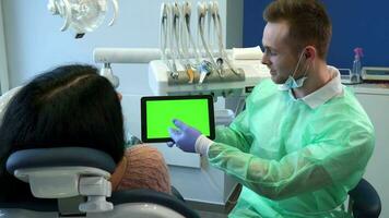 dentista punti il suo mano su tavoletta schermo video