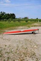 a red and white surfboard on the ground photo