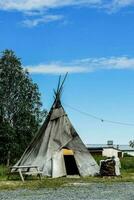 a teepee sits in the middle of a gravel lot photo