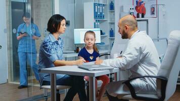 Pediatrician writing prescription for kid after examination. Healthcare practitioner, physician, specialist in medicine providing health care services consultation diagnostic treatment in hospital. photo