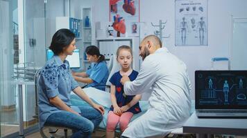 Little girl having annual medical checkup, doctor using stethoscope. Healthcare practitioner physician specialist in medicine providing health care services consultation treatment in hospital photo