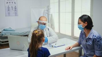 Doctor with protective gloves showing skeleton on tablet to girl. Physician specialist in medicine providing health care services consultation treatment examination in hospital cabinet during covid19 photo