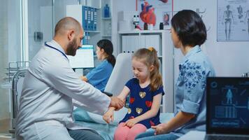 Doctor checking child injured arm and talking with mother. Healthcare practitioner physician specialist in medicine providing health care service radiographic treatment examination in hospital cabinet photo