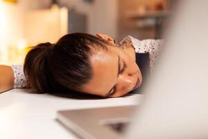 Overworked woman falling asleep in home kitchen late at night. Employee using modern technology at midnight doing overtime for job, business, busy, career, network, lifestyle ,wireless. photo