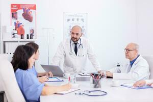 Doctor talking standing and talking with medical staff about treatment for patient. Clinic expert therapist talking with colleagues about disease, medicine professional. photo