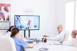 Medical physicians talking with medical specialist during teleconference. Medicine staff using internet during online meeting with expert doctor for expertise. photo