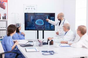 Team of doctors doing research about brain activity using headset with sensors. Monitor shows modern brain study while team of scientist adjusts the device. photo