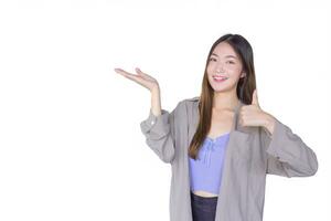 Beautiful young Asian woman wearing purple shirt is acting thumb up as good symbol and another hand shows as presenting something on the background. photo