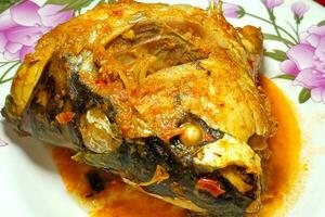 Fish head cooked with spices on a plate photo