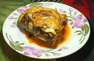 Fish head cooked with spices on a plate photo