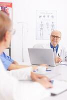 Medical expert talking with medical staff during healthcare meeting in hospital conference room. Clinic therapist talking with colleagues about disease, medicine professional photo