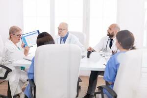 Medical staff gathered in conference room talking about patient disease. Clinic expert therapist talking with colleagues about treatment , medicine professional photo