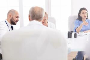 Young expert doctor talking with medical staff in conference room Clinic therapist dicussing with colleagues about disease, medicine professional photo