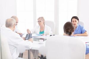 Team of expert doctors sitting at desk in conference room having a briefing. Clinic expert therapist talking with colleagues about disease, medicine professional photo