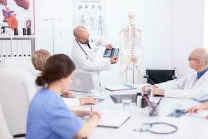 Expert doctor holding radiography during medical seminar for medical staff in conference room. Clinic therapist talking with colleagues about disease, medicine professional photo