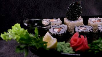 Sticks Take Sushi in restaurant lights background. Variety of types sushi with red caviar, fish, Philadelphia cheese and chopsticks closeup. Set of delicious Japanese sushi rolls on a stone board video