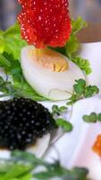 lyxig aptitretare av vaktel ägg med en klistra av bläckfisk, räka och svart kaviar på potatis och ost pommes frites video