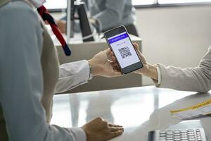 Passenger is showing online check in qr code boarding pass to the airline ground crew at departure gate counter into the airplane for final inspection before boarding into the  plane photo