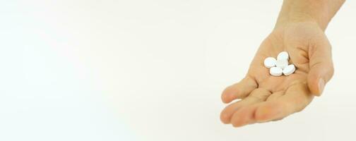 Old female hand with white pills on a white background. photo