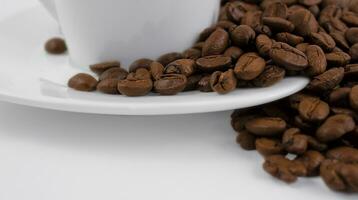 A cup of coffee and coffee beans on a white background. Roasted coffee beans on a white saucer, close up. photo