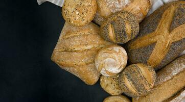 Freshly baked bread and rolls on a black background. Copy space. photo