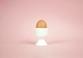 huevo en huevo taza en un rosado antecedentes. Pascua de Resurrección concepto. foto