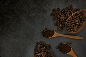 Ground coffee and roasted coffee beans in wooden spoons on a dark background. photo