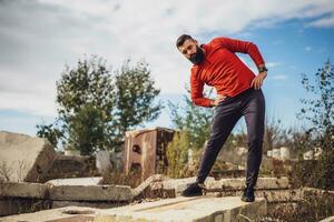 Adult man is exercising outdoor on sunny day. He is stretching his body. photo