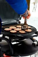 Man grilling steaks on a portable BBQ, Snowy winter barbecue photo