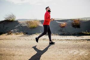 Adult man is jogging outdoor on sunny day. photo