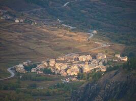 a small town on a hillside with a road winding through it photo