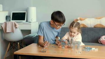 niños jugar con un metal constructor a el mesa a hogar.madres día, familia juegos, hogar educación,educativo juegos video