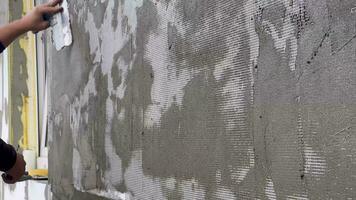 Closeup of a worker's hand with a trowel applying mortar to white mesh and rigid polyurethane foam for home insulation. video