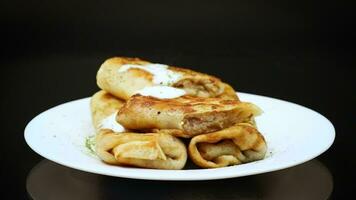 magro fritte Pancakes con carne Riempimento nel un' piatto con acida crema e spezie. video