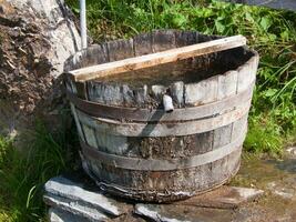 a wooden bucket sitting on a rock photo