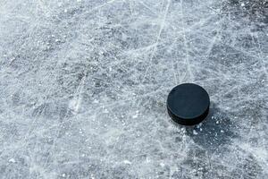 black hockey puck lies on ice at stadium photo