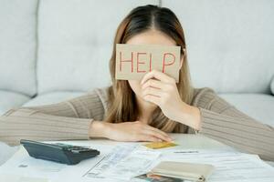 Stressed and headache asian woman with large bills or invoices no money to pay to expenses and credit card debt. shortage, Financial problems, mortgage, loan, bankruptcy, bankrupt, poor, empty wallet photo