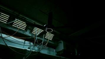 A ceiling fan with multiple wires attached to it in a dark concrete interior video