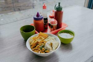 Bowl of Chicken Noodles on wooden table with chili sauce, sauce and meat sauce. Food, menu, dish and culinary concept. photo