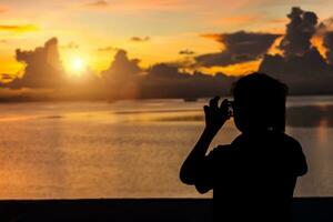 Silhouettes people shooting the sunset at the lake. photo