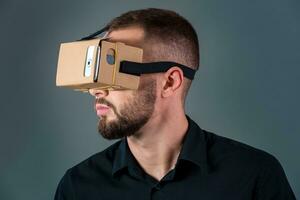 hombre utilizando un nuevo virtual realidad auriculares en gris antecedentes foto